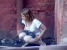 Girl pees in public next to old buildind