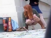 Zoom on a redhead girl pissing in an alley
