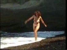 Chica de tetas grandes desnuda en la playa solitaria