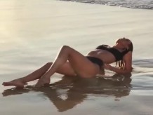 Candice Swanepoel recostada en la playa en bikini negro
