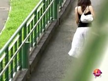 Nena asiática con una falda larga blanca es abusada en la calle.