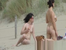 Chica en una playa nudista que broncea y dobla una playa nudista v
