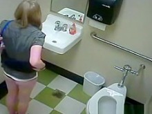 Rubia orinando en un baño público