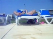 Mi esposa en la silla de salón estimula su clítoris junto a la piscina