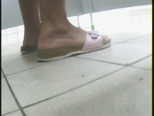 Una chica con zapatillas rosas está orinando para orinar.